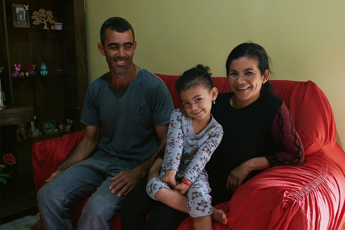 Nailton and Lucimar from Brazil sit next to their young daughter in their home.