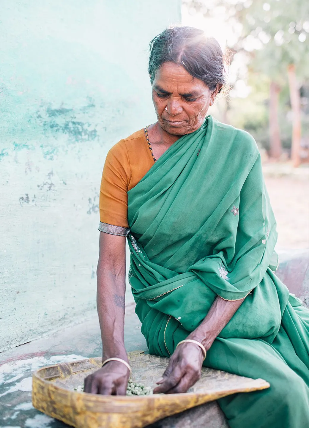 Woman wearing a green sari working outside her home in Mysore, India.